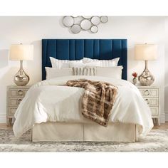 a bed with white linens, pillows and blankets on top of the headboard