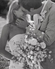 a man and woman kissing each other in front of a flower bouquet on their wedding day