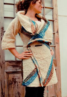 a woman standing in front of a wooden door wearing a knitted dress and boots