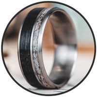 two wedding bands with silver and black inlays on each side, set inside a circle