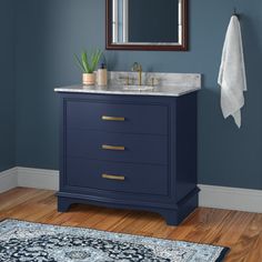 a bathroom with blue walls and wooden flooring, a mirror above the sink and a rug on the floor