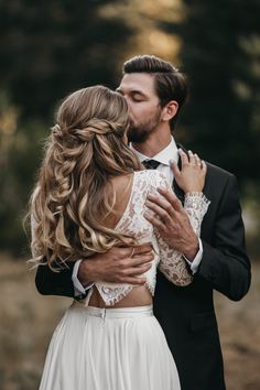 a man in a suit and tie kissing a woman with her arms around her neck