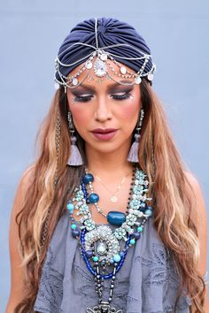 a woman with long hair wearing a blue headband and jewelry on her face,