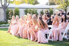 a group of women sitting next to each other on top of white chairs in front of a crowd