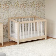 a white crib in a room with floral wallpaper