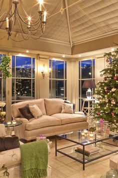 a living room filled with furniture and a christmas tree in front of two large windows