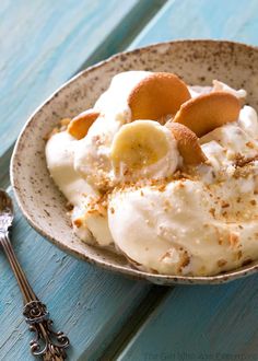 a bowl filled with ice cream and bananas on top of a table next to a spoon