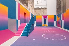 an indoor basketball court painted with multicolored paint and stairs leading up to it