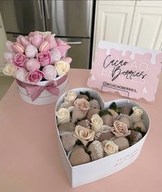 a heart shaped box filled with chocolates next to a bouquet of roses on a table