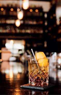 a glass filled with ice and lemons on top of a wooden table next to a bar