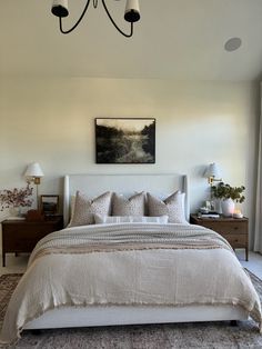 a large bed sitting under a chandelier next to a painting on the wall