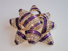 Stunning sparking Napier purple bow encrusted with Aurora Borealis glistening rhinestones. This gem would make a perfect Birthday gift to be enjoyed year round, as well as a conversation starter. Measures 1 3/4" X 2". pristine condition, signed Napier. Ready to be enjoyed by you, or given as a gift. This color brooch is extremely hard to find. Purple Rhinestones Brooch As A Gift, Purple Rhinestone Brooches As A Gift, Purple Rhinestone Brooches For Gifts, Purple Rhinestone Brooches As Gifts, Purple Rhinestone Party Brooches, Elegant Purple Rhinestone Brooches, Glamorous Bling Brooches As A Gift, Glamorous Bling Brooches As Gift, Purple Bow