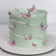 there is a green cake with pink butterflies on the frosting and white icing