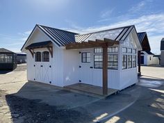 a small white building sitting on top of a dirt lot next to a blue sky