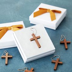 three wooden crosses sitting on top of a table next to a white box with gold ribbon