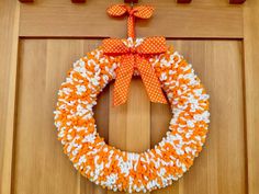 an orange and white wreath hanging on the front door with polka dot ribbon attached to it