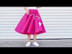 a woman in a white shirt and pink skirt is posing for the camera with her hand on her hip