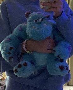 a woman taking a selfie with her cell phone while holding a blue teddy bear