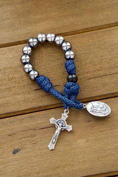 Crafted with exceptional attention to detail by our dedicated Sanctus Servo family, this rosary is built to endure life's challenges while keeping his faith strong and ever-present. The blue and black paracord ropes are not only visually striking but also extremely resilient, ensuring that it can withstand any task they may assign it to, from prayerful hikes to intense physical activities.Featuring 10mm gunmetal colored Hail Mary beads and matte black Our Father beads, this rosary is designed fo Rosary For Kids, Rosary Prayers Catholic, Paracord Rosary, Mini Rosaries, Divine Protection, Catholic Family, Rosary Prayer, Burlap Bows, Rosary Beads