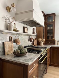 a kitchen with marble counter tops and wooden cabinets, along with hanging utensils