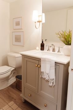 a white toilet sitting next to a sink in a bathroom under a vanity with a mirror above it