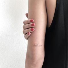 a woman's arm with a small tattoo that reads, love is in the air