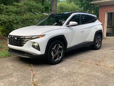 a white suv parked in front of a house