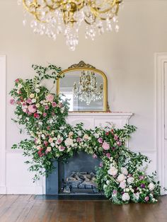 the fireplace is decorated with flowers and greenery for an elegant touch to the room