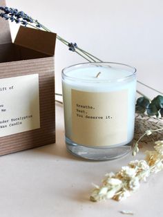 a candle sitting on top of a table next to a box with a note inside