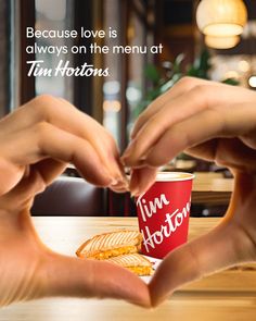 two hands reaching for a cup of coffee on a table with the caption, because love is always on the menu tim horton