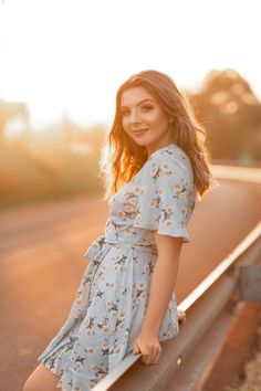 a beautiful young woman standing on the side of a road