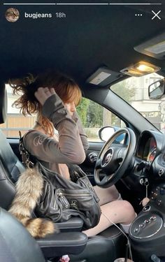 a woman sitting in the driver's seat of a car while holding her cat