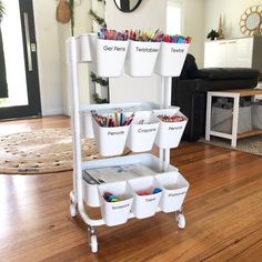 a white cart filled with lots of different colored pencils on top of a hard wood floor