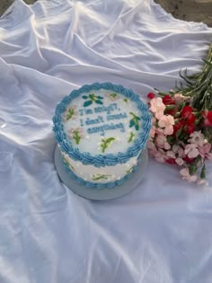 a blue and white cake sitting on top of a table next to some pink flowers