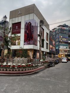 a large building with a lot of flowers in front of it and cars parked on the street