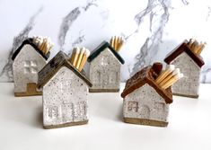 four ceramic houses with matches sticking out of them