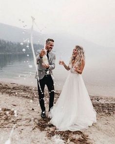 a bride and groom are throwing confetti at each other on the lake shore