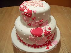 two tiered cake decorated with hearts on a table