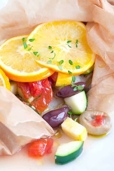 a white plate topped with sliced up oranges and cucumber next to a brown paper bag