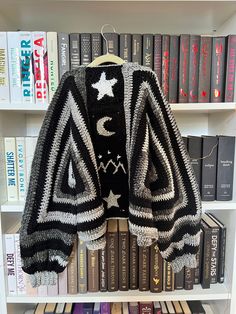 an open bookcase with books and a knitted jacket on it's shelf