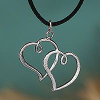 a silver pendant with two hearts hanging from it's side on a black cord