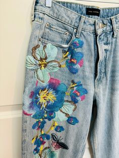 a pair of jeans with embroidered flowers on them