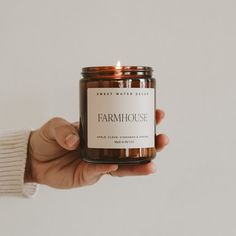 a person holding a candle in their hand with the label on it that says farmhouse house