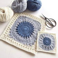 three crocheted grannys and two balls of yarn