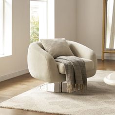 a white chair sitting on top of a wooden floor next to a mirror in a living room