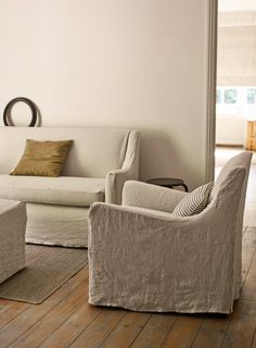 a living room with white furniture and wooden floors