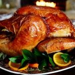 a roasted turkey on a plate with oranges and greens