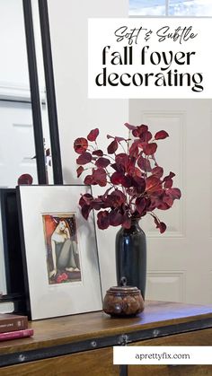 a vase with red flowers sitting on top of a wooden table next to a mirror