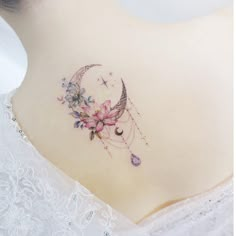 the back of a woman's neck with a flower and crescent tattoo on it