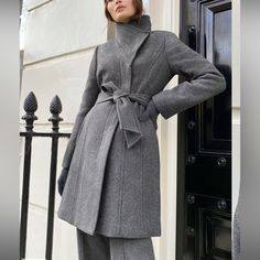 Stunning Italian Wool Coat In Excellent Condition - Never Worn. Light Grey Color. Features Warm To -10c / 14f Vegan Chamois Interlining For Lightweight Warmth Fully Lined High Funnel Neck Removable Belt Hidden Button Closure We Developed Our Warmth Ratings To Help You Choose The Right Coat For Your Climate, Activities And Needs. Because Everyone Feels Temperature Differently, They Are Intended As Guidelines Only. Materials & Care Origin: Fabric From Italy Content: 95% Virgin Wool, 5% Polyamide; Fitted Wool Coat With Belted Cuffs For Office, Chic Fitted Wool Coat With Belted Cuffs, Chic Fitted Outerwear With Belted Cuffs, Elegant Fitted Wool Coat With Belted Cuffs, Fitted Winter Outerwear With Belted Cuffs, Fitted Wool Outerwear With Belted Cuffs, Fitted Wool Coat With Belted Cuffs For Winter, Chic Fitted Wool Coat For Work, Fitted Wool Coat With Stand Collar For Work